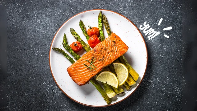 A plate of Baked Salmon with Asparagus, featuring flaky salmon and tender asparagus on a marble countertop in a modern kitchen.