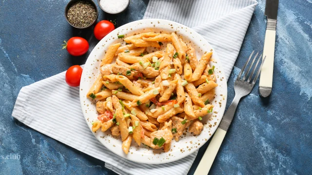 A bowl of Cajun Chicken Pasta with creamy sauce and tender chicken pieces on a marble countertop in a modern kitchen.