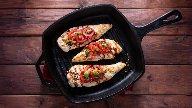 grilled chicken breasts in a cast iron skillet on a wooden table