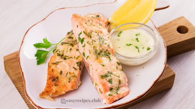 A plate of Lemon Dill Salmon garnished with fresh dill and lemon slices on a marble countertop in a modern kitchen.