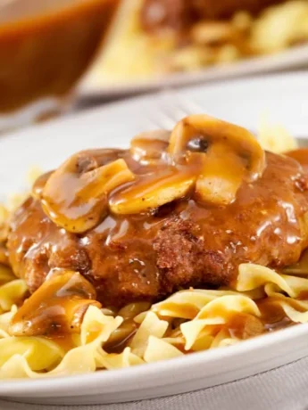 two plates topped with meat and noodles, Salisbury Steak recipe