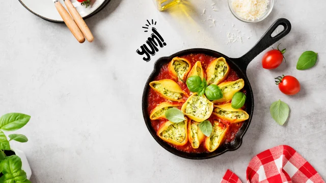 A plate of Spinach and Ricotta Stuffed Shells baked in marinara sauce on a marble countertop in a modern kitchen.