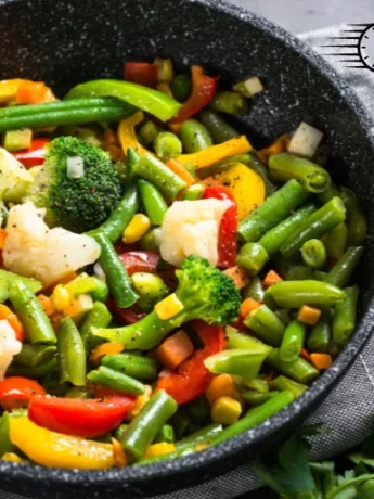 Delicious vegetable stir fry with a variety of vegetables such as carrots, broccoli, and bell peppers, topped with sesame seeds and served in a modern white bowl.