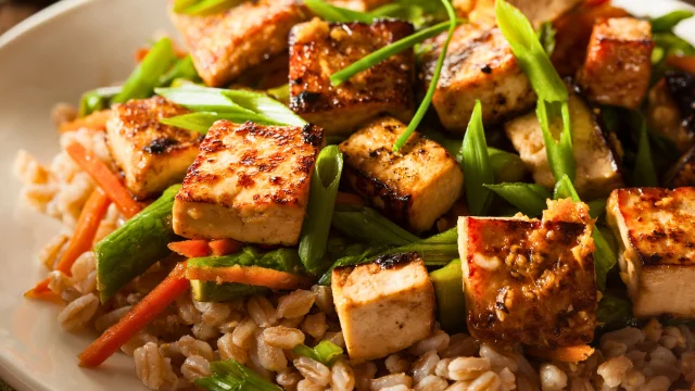 A vibrant Veggie-Packed Stir-Fry, featuring a mix of colorful vegetables like bell peppers, broccoli, carrots, and snap peas, stir-fried with tofu in a savory sauce. Garnished with sesame seeds and served over a bed of steamed rice
