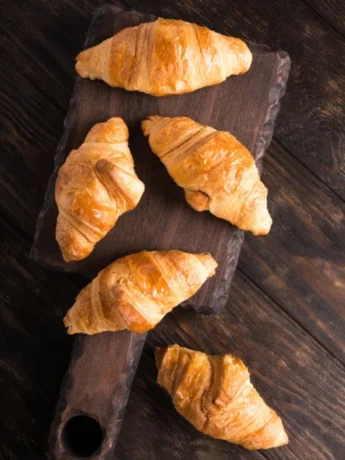 Golden brown Gipfeli croissants cooling on a wire rack in a modern American kitchen.