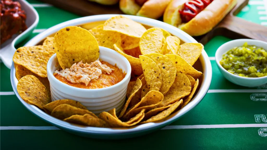 A bowl of Buffalo chicken dip ready to be served with a side of celery sticks.